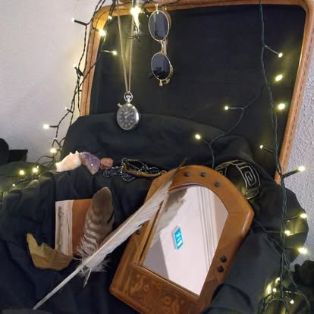Avonaisessa vanhassa matkalaukussa on sisällä musta kangas, valoketju, antiikilta näyttävä peili, suuri ja pieni sulka, kulunut vihko, taskukello ja aurinkolasit. Tunnelma on maaginen.